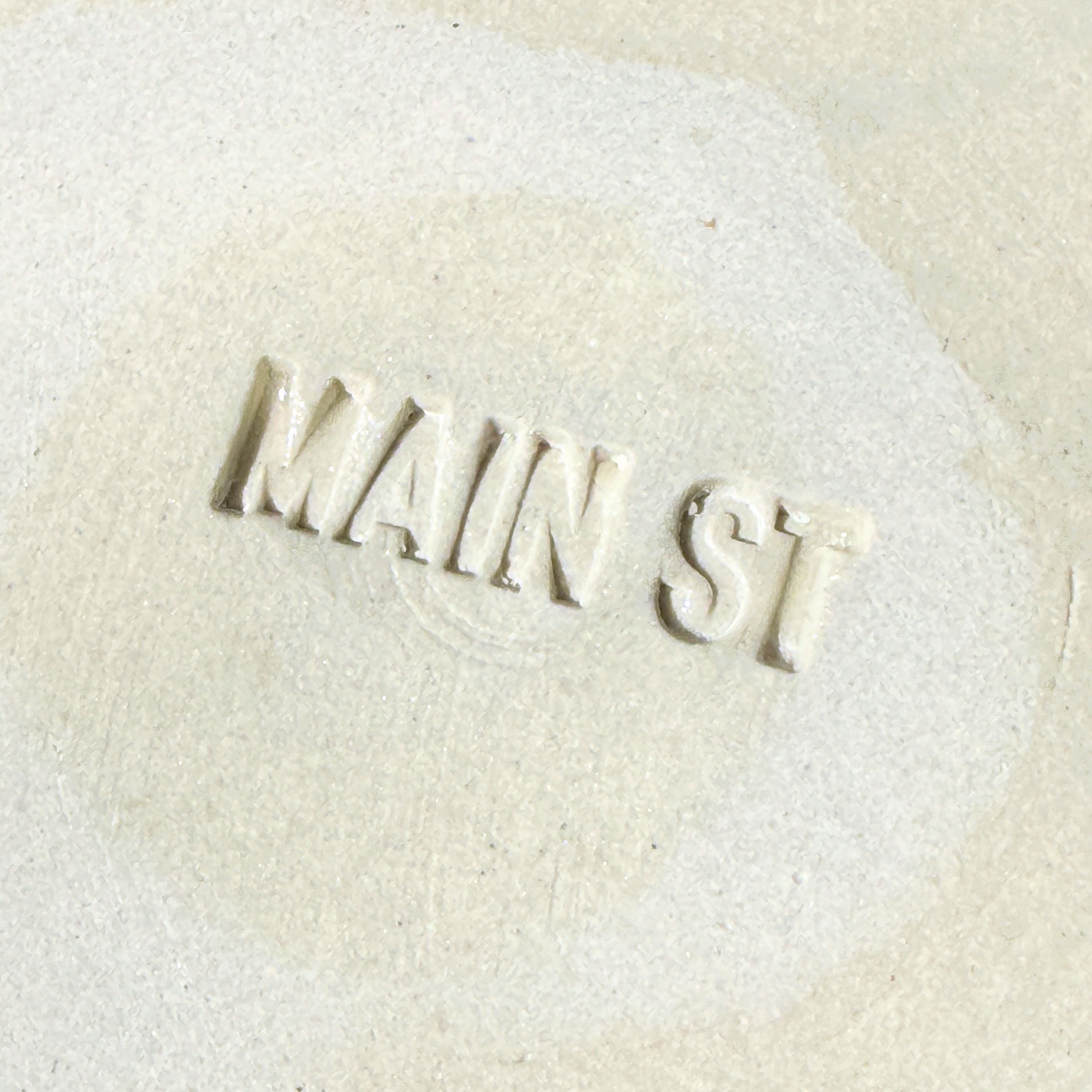 Text 'MAIN ST' embossed on a textured beige surface