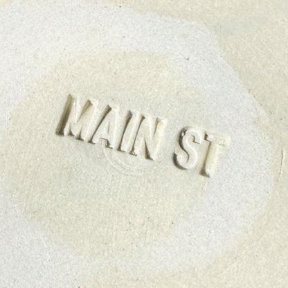 Text 'MAIN ST' embossed on a textured beige surface